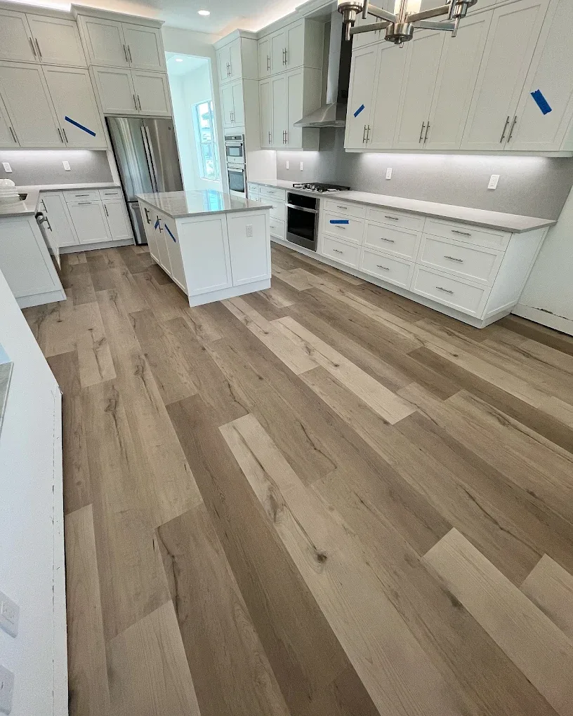 Wide-plank luxury vinyl flooring installed in a bright white Naples kitchen by Enterprise Floors